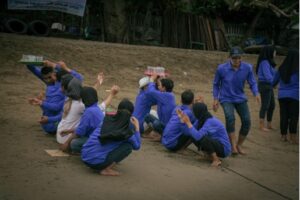 Permainan outbound pantai, tim bekerja sama membawa gelas air